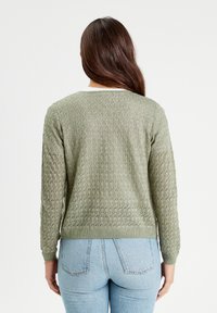Hellgrüner, gestrickter Pullover mit einem strukturierten offenen Gewebe, langen Ärmeln und geripptem Saum. Entworfen mit einem runden Halsausschnitt.