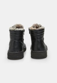 Botas de tobillo de cuero negro con forro de pelo sintético, diseño acanalado en la parte superior y suela de goma, con cremalleras a ambos lados.