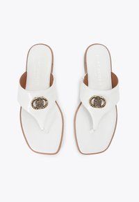 Sandali piatti bianchi con punta arrotondata, dotati di una fibbia decorativa dorata e una tomaia in similpelle liscia, montati su una suola beige.