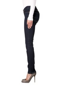 Jeans ajustados de mezclilla oscura, diseño de tiro medio, con dos bolsillos traseros y costuras sutiles. Llevados con zapatos de tacón grises.