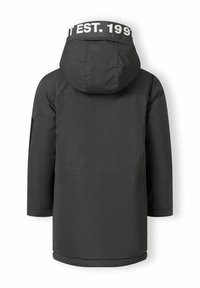 Svart parkerjacka med huva, med en vit märkesetikett "EST. 1997" vid nacken, och ett vattentåligt material. Enkelt design.