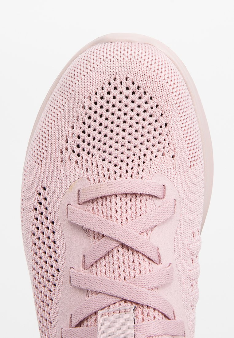 Zapatilla de color rosa claro con parte superior de punto transpirable y detalles de malla, cordones planos y suela de goma ligera.