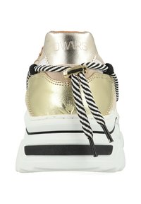 Sneaker met een metallic gouden en beige suede bovenwerk, zwart-witte gestreepte veters en een chunky witte zool met zwarte accenten.