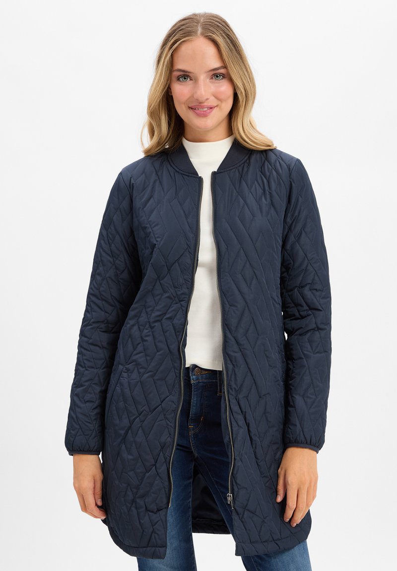 Marineblau gesteppter langer Mantel mit Reißverschluss, Rundhalsausschnitt und gerippten Bündchen. Verfügt über ein Rautenmuster und Seitentaschen.