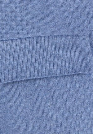 Close-up van lichtblauw gebreid stof met gedetailleerde geribbelde en gestructureerde steekpatronen.