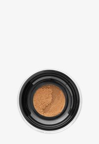 Polvo mineral suelto en un envase transparente con tapa negra. El polvo es de un tono bronceado cálido, con una textura fina y un tamiz de malla.