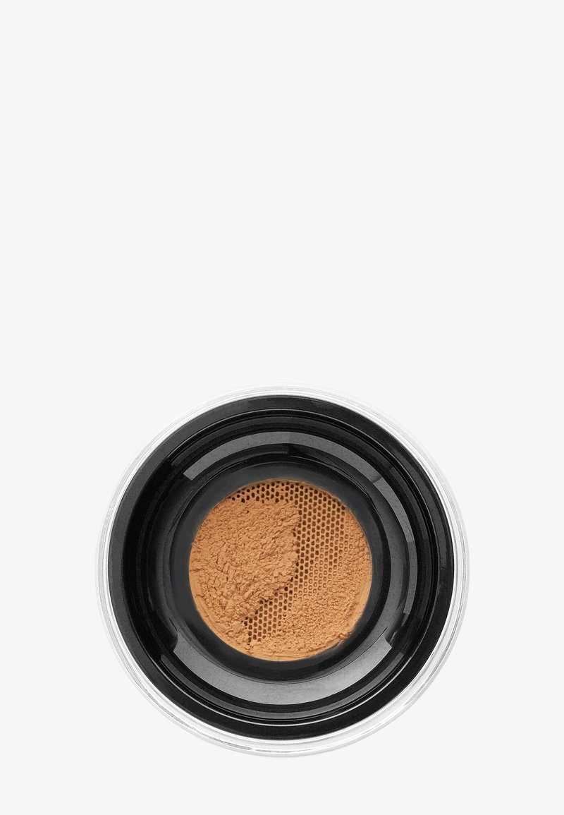 Polvo mineral suelto en un envase transparente con tapa negra. El polvo es de un tono bronceado cálido, con una textura fina y un tamiz de malla.