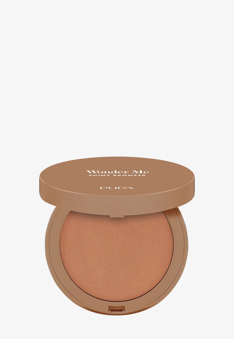 Kompaktowy bronzer o gładkiej, kremowej konsystencji. Zawiera błyszczący, brązowy puder w okrągłym beżowym etui z wyraźnie widoczną etykietą „Wonder Me”.