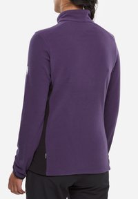 Purple fleece jacket with a high collar, long sleeves, textured fabric, and black side panels. Features a small logo on the left sleeve.