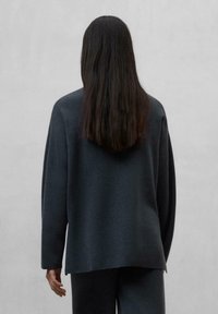Grå oversized tröja med långa ärmar, len textur och rundade fåll, ihop med matchande grå byxor.