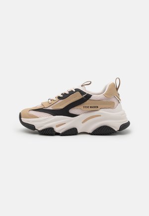 Beige en zwarte sneakers met mesh panelen, dikke witte zool en veters. Kenmerkt zich door een merkdetail aan de zijkant en een gestructureerde rubberen buitenzool.