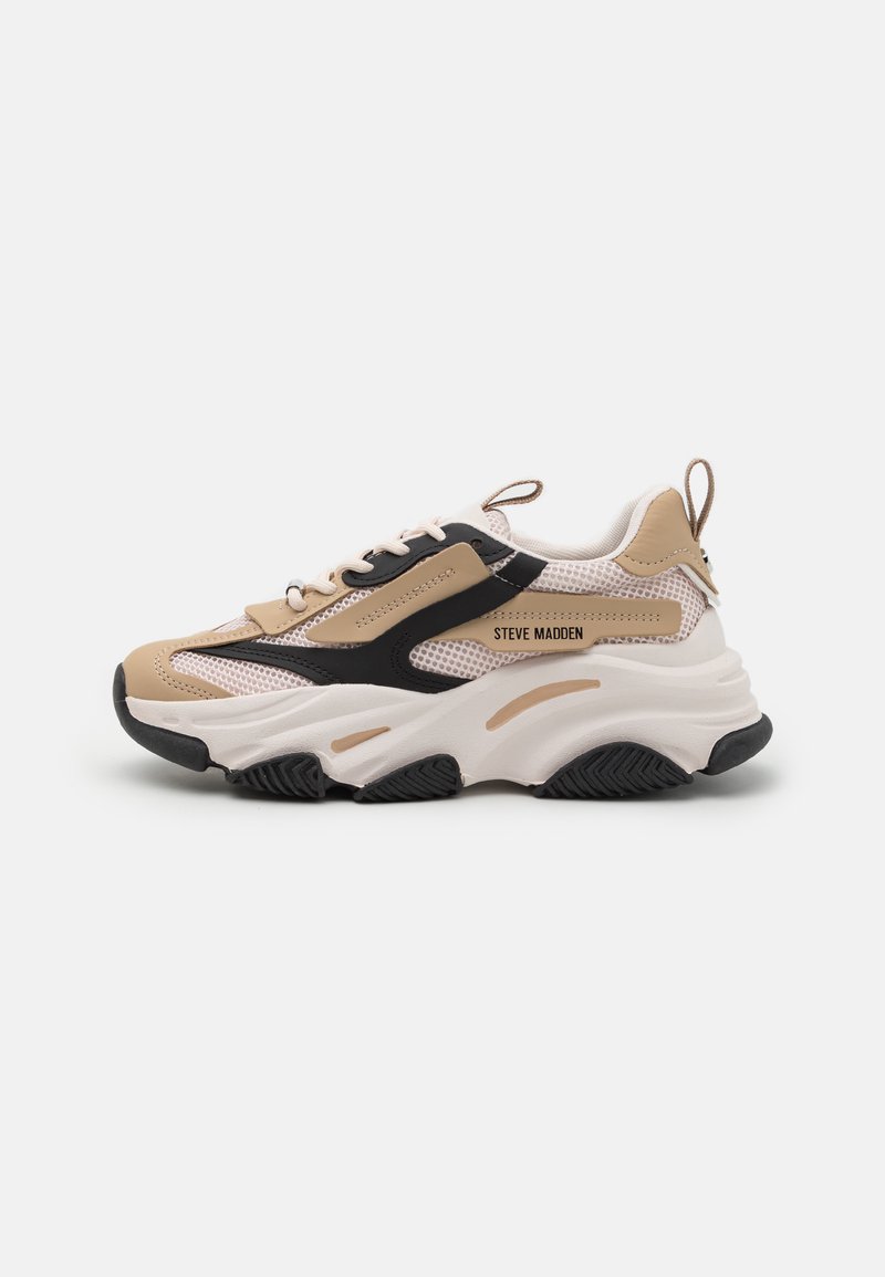 Beige and black sneakers with mesh panels, thick white sole, and laces. Features branded detail on the side and textured rubber outsole.