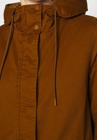 Brun huvad jacka i slät tyg med knappstängning, dragskoaccent och mjukt innertyg.