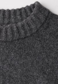 Pull en laine gris avec un col montant côtelé et une finition douce et texturée. Le tissu semble épais et chaud, adapté aux temps froids.