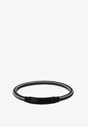 Fascia per capelli elastica intrecciata bianco e nero con fibbia in plastica nera di forma circolare su sfondo bianco.