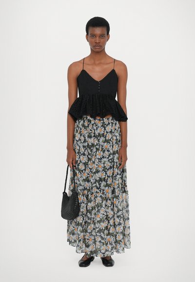 Schwarzes Peplum-Top mit Spitzenakzenten, Knopfleiste; fließender Maxirock mit floralem Muster in Weiß und Orange; schwarze geflochtene Handtasche; schwarze Schuhe.