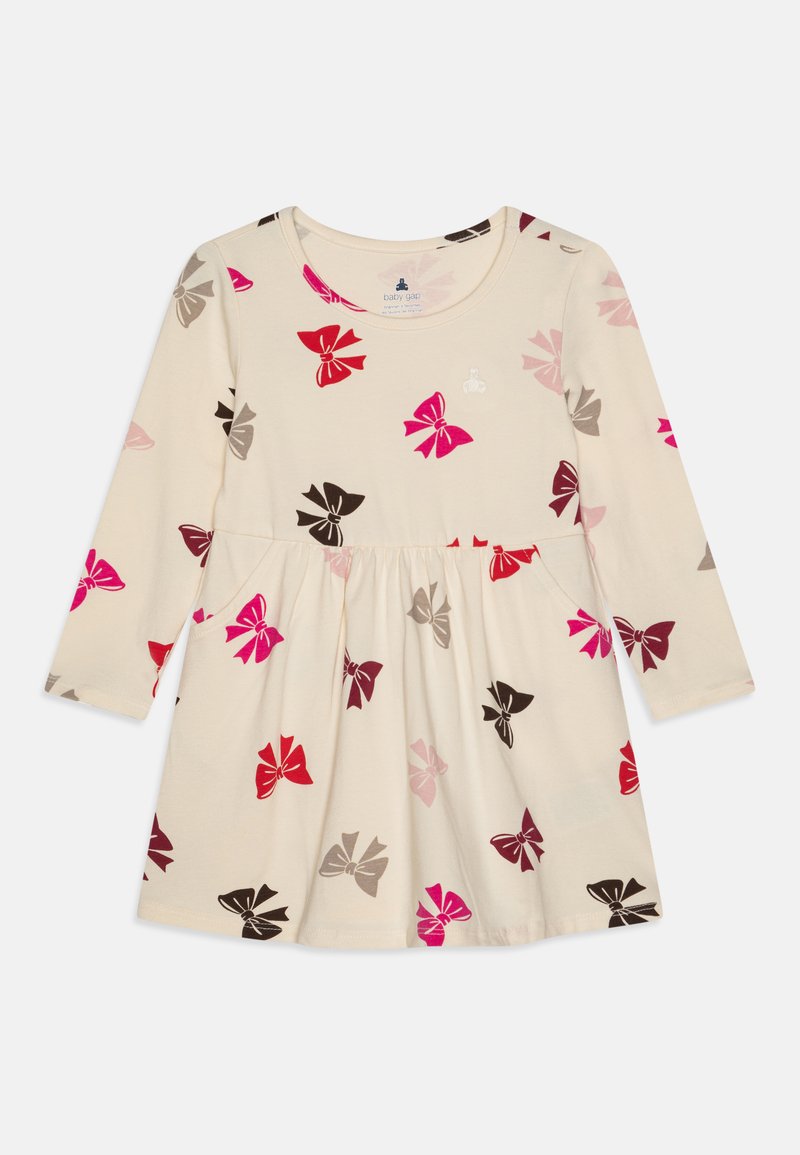 Ljus beige långärmad klänning med en utsvängd kjol, prydd med ett mönster av färgglada rosetter i rosa, röd, brun och grå. Inkluderar fickor.