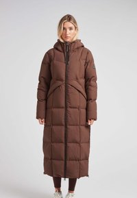 Abrigo acolchado marrón con capucha, cremallera completa y bolsillos laterales; presenta un diseño geométrico y una textura suave y lisa.