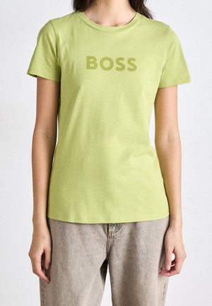 Zelené bavlněné tričko s kulatým výstřihem a krátkými rukávy, s nápisem "BOSS" potištěným v kontrastní barvě na přední straně.