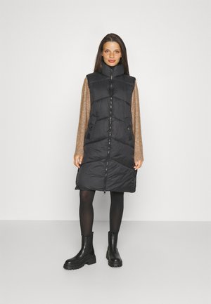Gilet en duvet noir avec col montant, doté d'une fermeture éclair, de poches latérales et d'une coupe jusqu'aux genoux. Le matériau est lisse et brillant.
