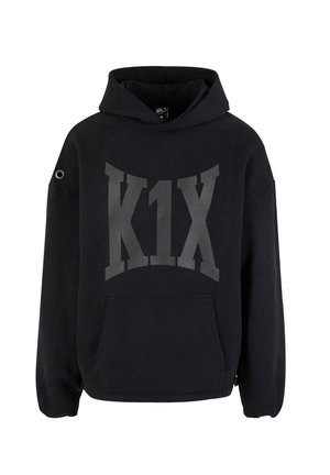 Black hooded sweatshirt with large gray "K1X" logo, front pocket, oversized fit, and eyelet detail on the left sleeve.