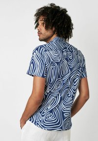 Kurzarmhemd aus navyblauem Baumwollstoff mit weißen abstrakten Wirbelmustern, mit einem kragenlosen Ausschnitt und einer lockeren Passform.