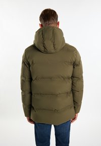 Olivengrøn pufferjakke med hætte, der har syede paneler og en lidt længere bagkant. Materialet virker glat og isoleret.