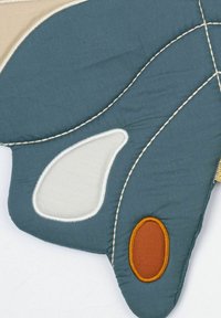 Textilní nástěnná dekorace ve tvaru motýla, obsahující části v tyrkysové, krémové a oranžové barvě, obrysovaná kontrastním prošíváním pro texturu.