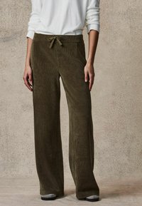 Spodnie z szerokimi nogawkami w oliwkowym zielonym kolorze, z elastycznym paskiem w talii i przednimi kieszeniami. Teksturowana tkanina z wiązaniem w talii.