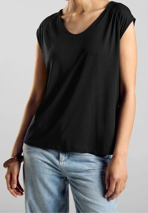 Zwart T-shirt met korte mouwen en een ronde hals, gemaakt van gladde stof; gecombineerd met lichtblauwe spijkerbroek en een bruin armbandje.