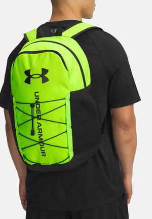 Hellem grünen Under Armour-Rucksack mit schwarzen Akzenten, ausgestattet mit einem Netzfach und Bungee-Seil-Details für sicheren Stauraum.
