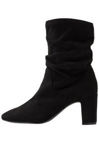 Černá semišová kotníková bota se sklopeným svrškem, špičatou špičkou a robustním podpatkem. Hladký povrch bez viditelných vzorů nebo kovových detailů.
