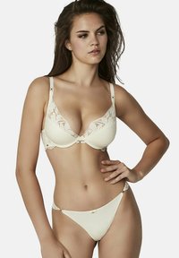 Crème-kleurig beha en string set met kantaccenten, met een diepe halslijn, verstelbare bandjes en decoratieve hardware details.