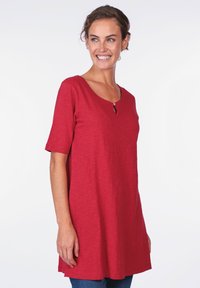 Red, short-sleeve tunic top, featuring a scoop neckline with a small keyhole detail, made from soft, textured fabric.