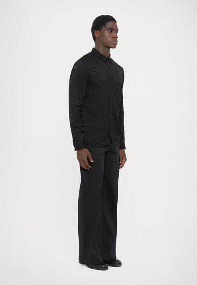 Black button-up shirt with a subtle textured floral pattern, worn with tailored black trousers and black shoes, featuring a straight silhouette.