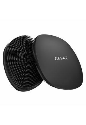 Twee zwarte siliconen gezichtsreinigingspads, één met zachte borstelharen en de ander met het merk "GESKE" op een glad oppervlak.