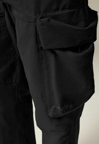 Pantaloni cargo negri, realizați dintr-un material neted, cu o mare buzunar laterale și detalii de cusătură. Include etichetă de marcă pe partea inferioară a piciorului.