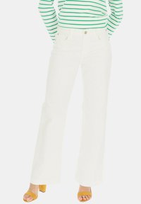 Białe jeansy w fasonie dzwonów wykonane z denimu, z pięcioma kieszeniami, szlufkami na pasek oraz złotym guzikiem w talii. Gładka tekstura, minimalne detale.