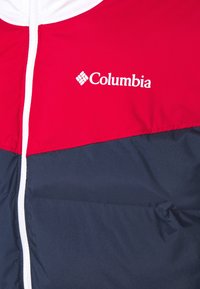 Rote und marinefarbene Daunenjacke mit weißem Reißverschluss, mit Columbia-Logo auf der Brust, aus glattem, leichtem Stoff.
