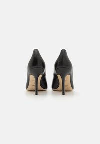 Scarpe nere in pelle con tacco alto, design a punta e sottile tacco a stiletto. Texture liscia con dettagli minimalisti.