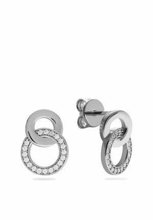 Boucles d'oreilles en argent avec deux boucles circulaires entrelacées, l'une lisse et l'autre ornée de petits cristaux clairs.