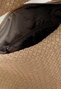 Beige szövött bőrtáska sima textúrával és átlós mintával, sötét béléssel és belső cipzáras zsebből.