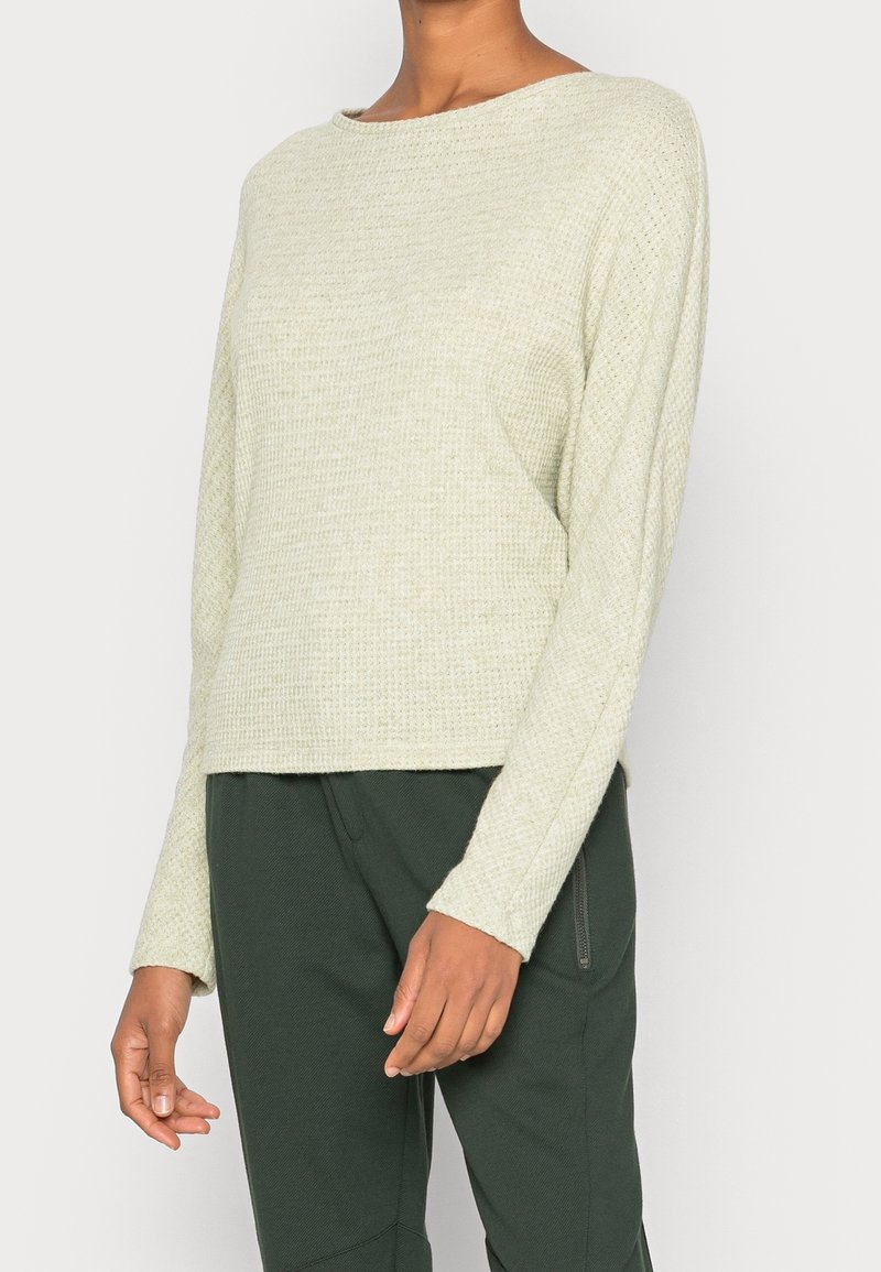 Lichtgroene lange mouwen textuurtrui met een bootnek, met een relaxte pasvorm en een rechte zoom, gedragen met donkergroene broek.