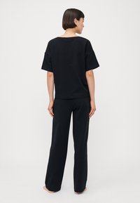 Zwarte casual outfit bestaande uit een losse korte mouw top en wijde broek, beide in een zachte, textuurstof.