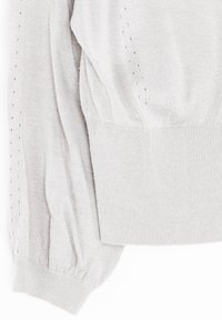 Ljust gråstickad tröja med ribbade ärmar och nederkant. Har ett strukturerat mönster med små hål längs ärmen. Mjuk och varm tyg.