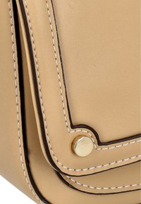 Tan lædertaske med hjørner og hvid syning, der har en guldknap som accent og en glat overflade. Enkel, rektangulær form med en lågflap.