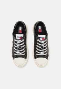 Czarne sneakersy z gładką skórzaną cholewką, białym gumowym czubkiem, srebrnymi sznurówkami oraz tkaninowym logo na języku.