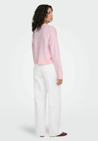 Light pink cropped sweater with long sleeves, paired with white wide-leg pants. The sweater features a ribbed hem and a relaxed fit.