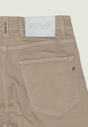 Beige Replay blue jeans med baglomme med let sømdesign og lille rødt "R" samt hvidt mærkebånd på taljen.