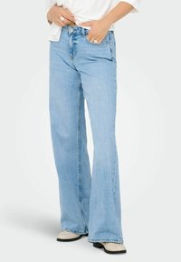 Lyseblå vidde jeans laget av denim, med høy midje, femlommers design og subtilt falmet detaljer på fronten.